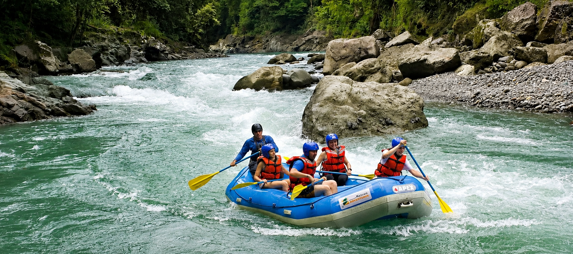Family group rafting through a lush river gorge